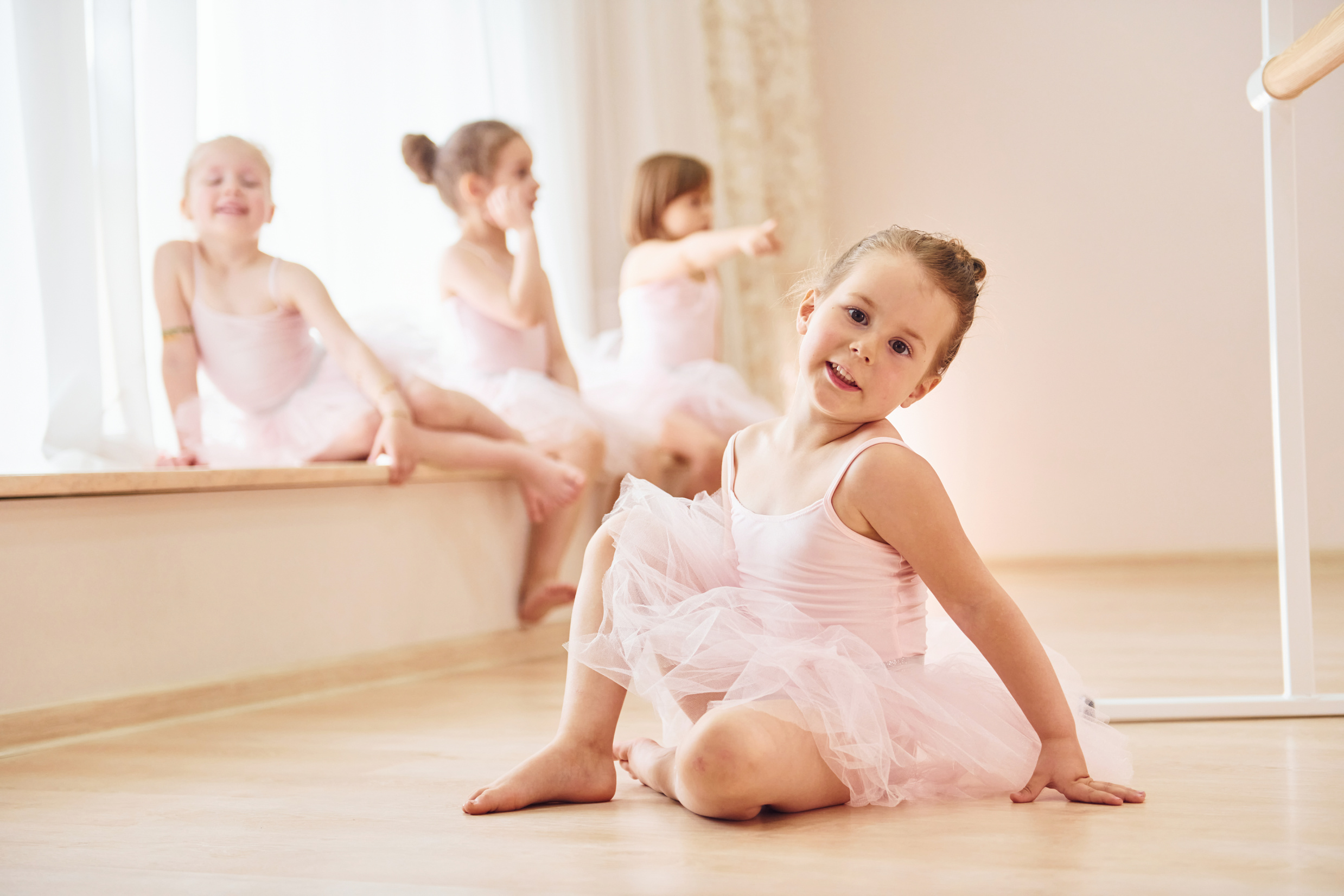 Girls sits on windowsill and on the floor. Little ballerinas preparing for performance